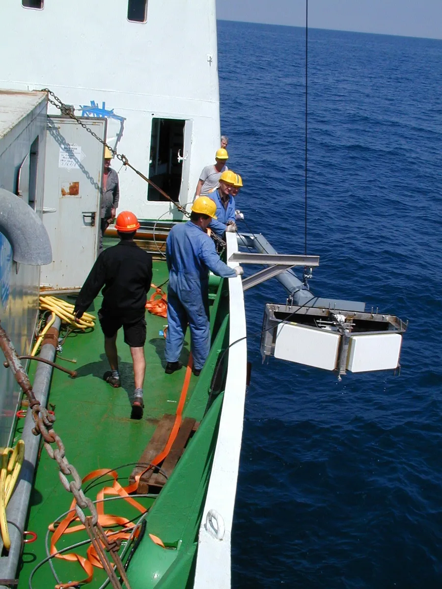Kru menurunkan transducer multibeam echosounder dari sisi kapal riset